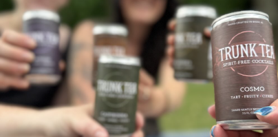 Cheersing of Trunk Tea Spirit-Free Cocktails cans at an outdoor picnic